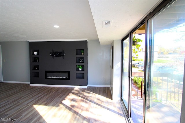 interior space featuring a wall of windows, a textured ceiling, a healthy amount of sunlight, and hardwood / wood-style flooring