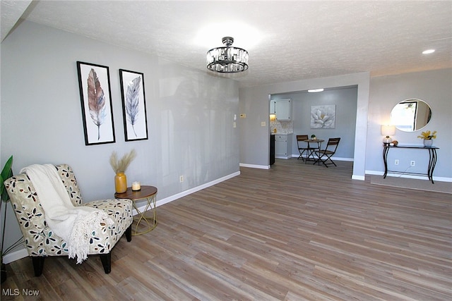 sitting room with a textured ceiling, hardwood / wood-style flooring, and a chandelier