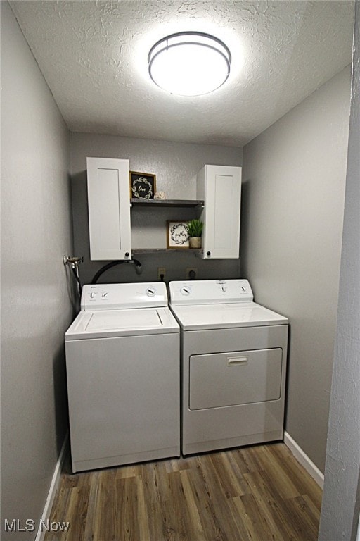 washroom with cabinets, a textured ceiling, separate washer and dryer, and dark hardwood / wood-style flooring