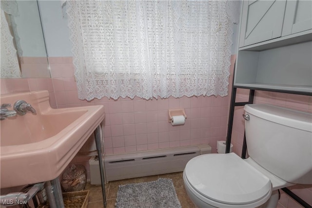 bathroom with baseboard heating, tile walls, tile patterned floors, and toilet