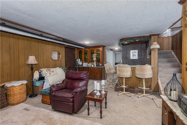 carpeted living room featuring bar and wooden walls