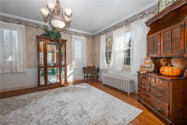 interior space with hardwood / wood-style flooring, radiator, crown molding, and an inviting chandelier