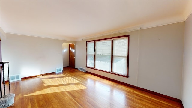 unfurnished living room with wood-type flooring and ornamental molding