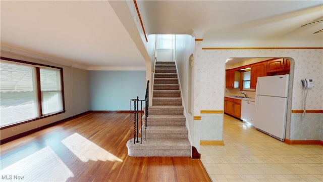 staircase with ornamental molding, sink, hardwood / wood-style flooring, and ceiling fan