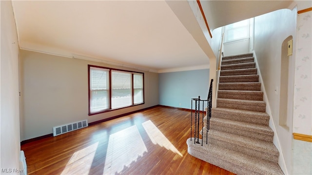 staircase with wood-type flooring and ornamental molding