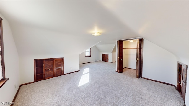 bonus room featuring vaulted ceiling and light colored carpet