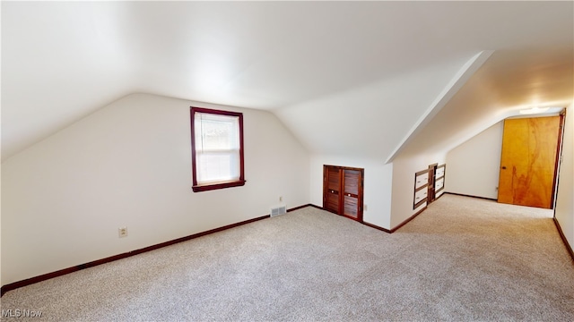 additional living space featuring light colored carpet and vaulted ceiling