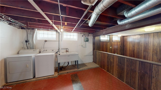 laundry room featuring sink, wooden walls, and washing machine and clothes dryer