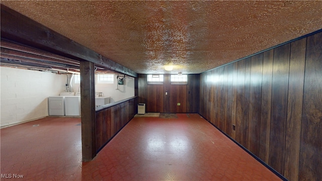 basement featuring sink, independent washer and dryer, and wood walls