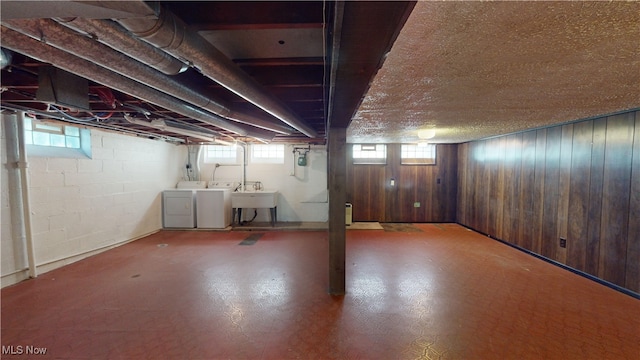 basement with wooden walls, sink, separate washer and dryer, and a wealth of natural light