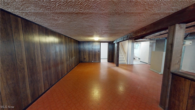 basement featuring a textured ceiling and wooden walls