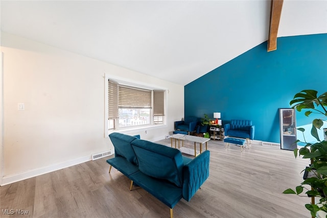 living room featuring lofted ceiling with beams and light hardwood / wood-style flooring