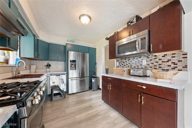 kitchen with exhaust hood, a textured ceiling, light hardwood / wood-style flooring, sink, and stainless steel appliances