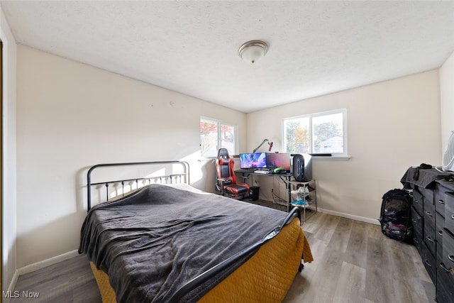 bedroom with a textured ceiling and light hardwood / wood-style floors