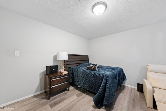 bedroom featuring light hardwood / wood-style floors and a textured ceiling