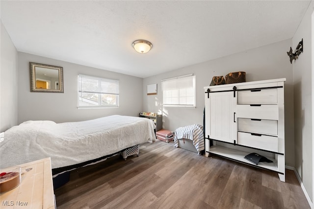 bedroom featuring hardwood / wood-style flooring, a textured ceiling, and a barn door