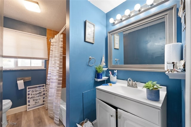 full bathroom with hardwood / wood-style flooring, toilet, shower / tub combo with curtain, vanity, and a textured ceiling