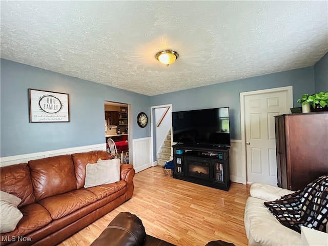 living room featuring a fireplace, a textured ceiling, and light wood-type flooring