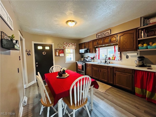 kitchen with a textured ceiling, dark brown cabinetry, sink, hardwood / wood-style flooring, and stainless steel range with gas cooktop