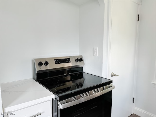 kitchen with light stone counters and stainless steel range with electric stovetop