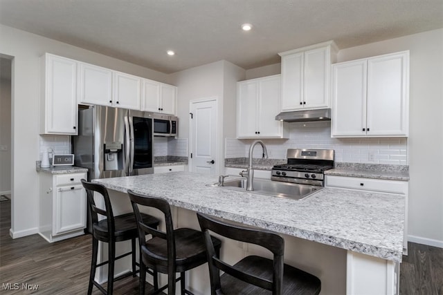 kitchen featuring a breakfast bar, appliances with stainless steel finishes, white cabinets, and an island with sink