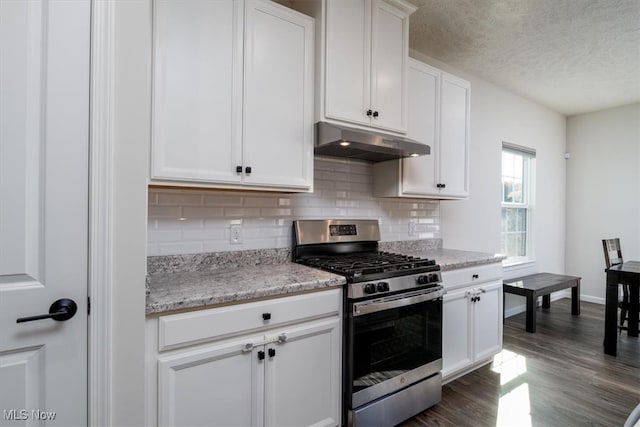 kitchen featuring light stone countertops, stainless steel gas range oven, white cabinets, dark wood-type flooring, and decorative backsplash