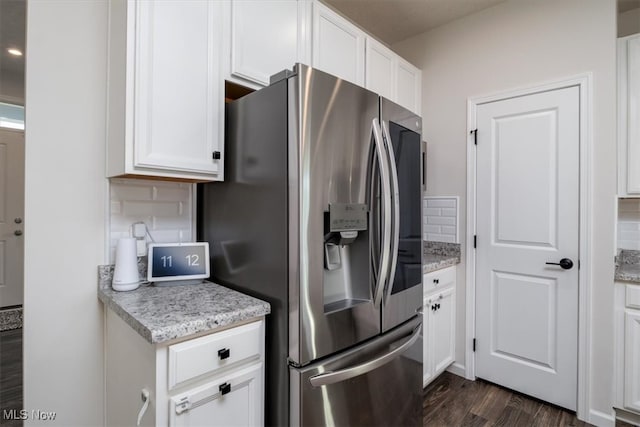 kitchen featuring white cabinets, light stone countertops, dark hardwood / wood-style floors, and stainless steel fridge with ice dispenser