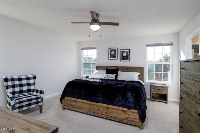 bedroom featuring ceiling fan, a textured ceiling, multiple windows, and light colored carpet