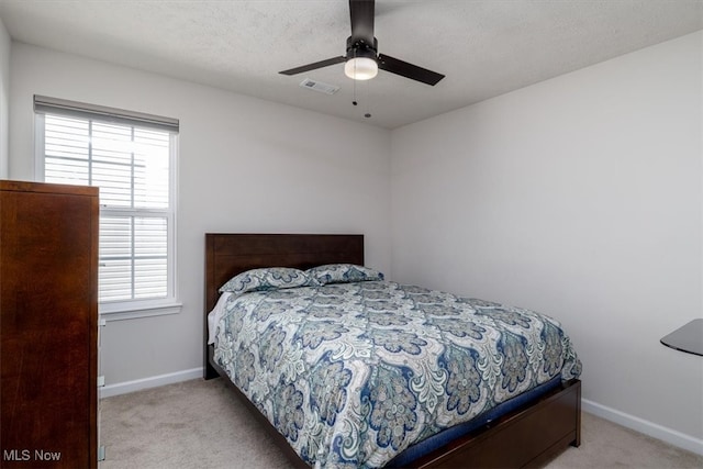 bedroom featuring ceiling fan, light carpet, and a textured ceiling