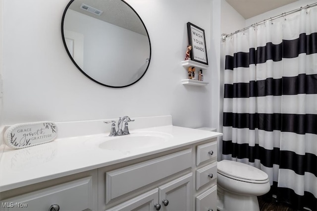 bathroom featuring vanity, walk in shower, and toilet