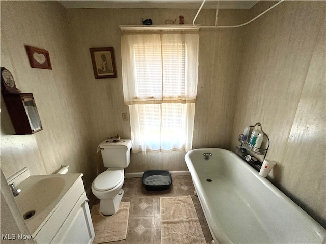 bathroom with toilet, vanity, and a bath