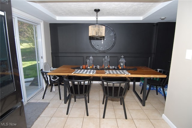 dining room featuring light tile patterned floors, a textured ceiling, and a tray ceiling