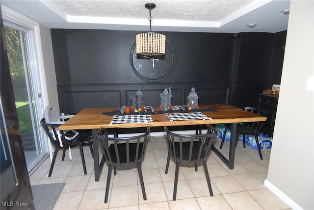 tiled dining space with a raised ceiling