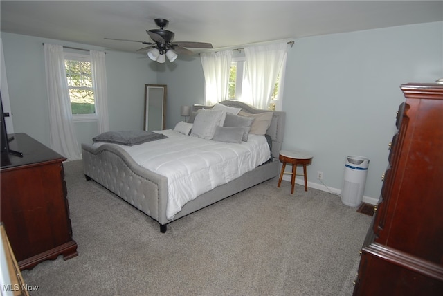 carpeted bedroom featuring multiple windows and ceiling fan