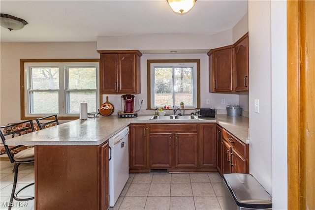 kitchen featuring dishwasher, kitchen peninsula, sink, and a breakfast bar area