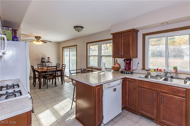 kitchen featuring a wealth of natural light, kitchen peninsula, sink, and white appliances