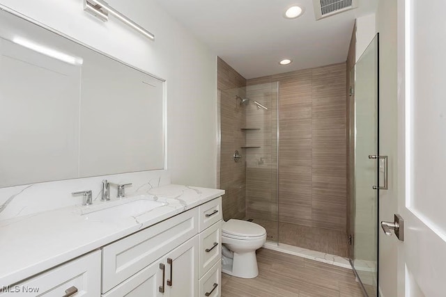 bathroom with toilet, a shower with shower door, and vanity