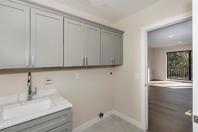 washroom featuring sink, electric dryer hookup, light hardwood / wood-style floors, and cabinets