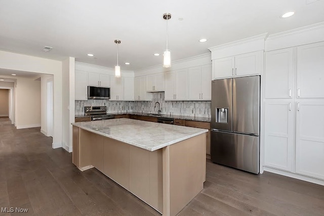 kitchen featuring light stone countertops, a center island, white cabinets, appliances with stainless steel finishes, and dark hardwood / wood-style flooring