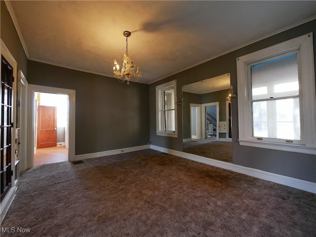 spare room with carpet flooring, ornamental molding, and a chandelier