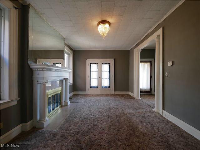 unfurnished living room with french doors, ornamental molding, and light colored carpet