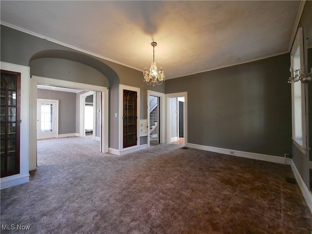 carpeted spare room with an inviting chandelier and crown molding