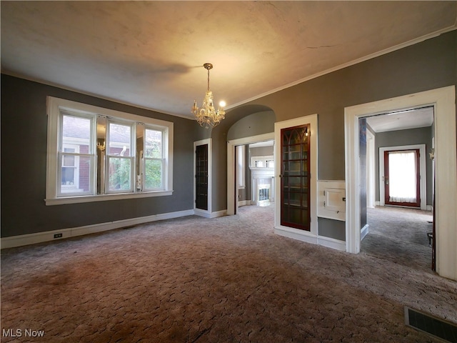 spare room with crown molding, carpet floors, a healthy amount of sunlight, and a notable chandelier