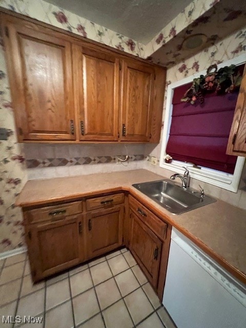 kitchen featuring white dishwasher, sink, and light tile patterned floors