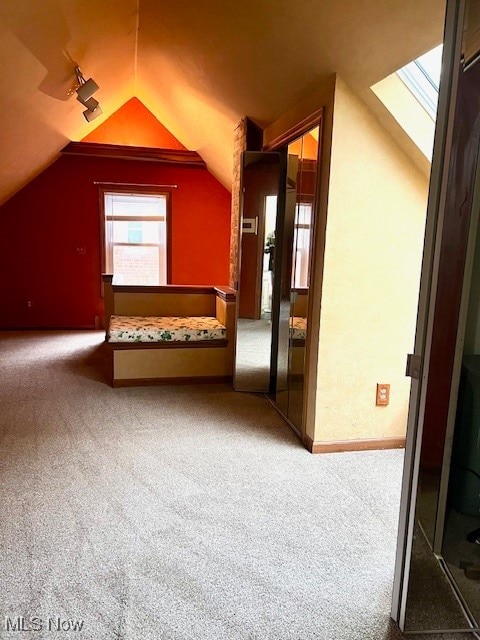 additional living space featuring lofted ceiling with skylight and carpet