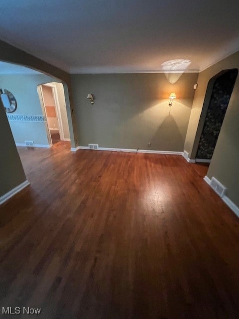 unfurnished room with ornamental molding and dark wood-type flooring