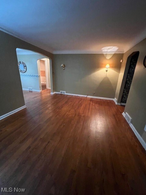 spare room featuring crown molding and dark wood-type flooring