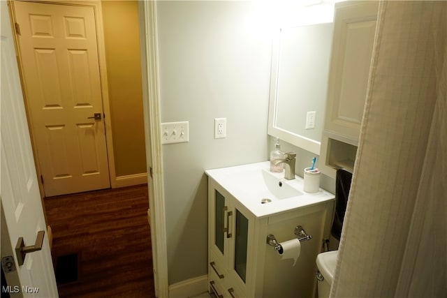 bathroom with toilet, hardwood / wood-style floors, and vanity