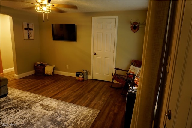 living area with ceiling fan, a textured ceiling, and dark hardwood / wood-style flooring