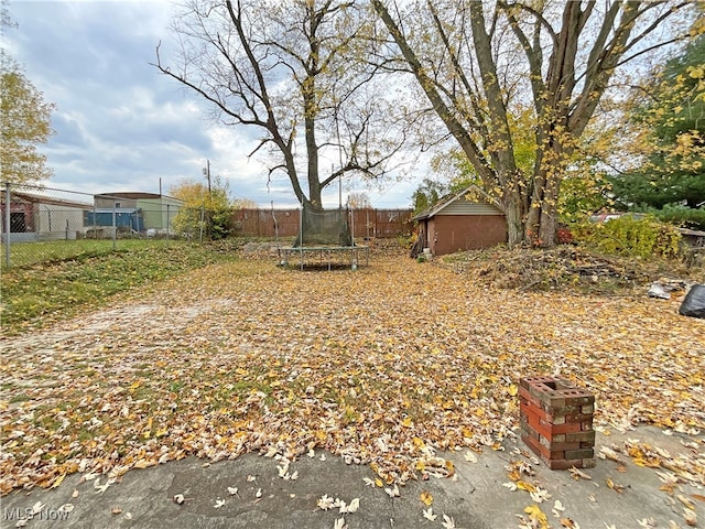 view of yard with a trampoline and an outdoor structure